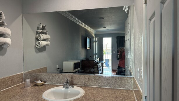 A bathroom with a sink, mirror, and towels on a rack. - Hiland Motel (Long Beach)