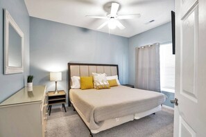 A bedroom with a bed, bedside table, lamp, and a ceiling fan.