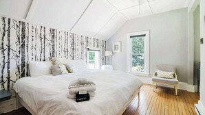 A bedroom with a large bed, a bedside table, a chair, and a window. - Bridgewalk Estate | a Wanderlust Abodes property (Central Lake)