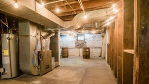A basement with exposed concrete walls, a water heater, and wooden barrels. - Bridgewalk Estate | a Wanderlust Abodes property (Central Lake)