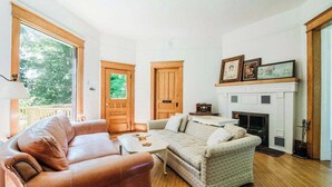 A living room with a fireplace, two sofas, a coffee table, and a door leading to another room. - Bridgewalk Estate | a Wanderlust Abodes property (Central Lake)