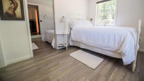 Une chambre à coucher avec un lit, une table de chevet, une lampe et une fenêtre.