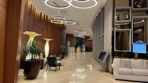 A modern lobby with a curved wooden wall, a white sofa, and a reception desk. - Amazing Ocean Views at LYFE Resort @rent4us (Hollywood)