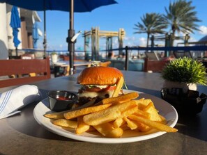 Une assiette avec un hamburger et des frites, posée sur une table en plein air.
