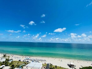 Une plage avec un ciel dégagé, une mer calme et quelques personnes.