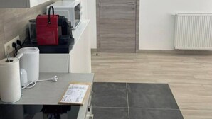 A modern kitchen with a black countertop, a red appliance, and a grey door.