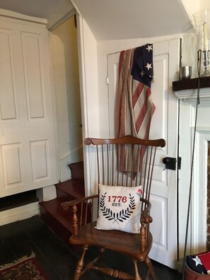 Sit comfortably in a traditional setting with a cozy fireplace and a vintage door adorned with a striped curtain and American flag.