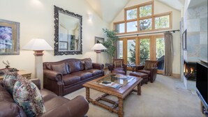 A spacious living room with a large brown leather sofa, a wooden coffee table, and a fireplace. - Luxury Lodge with Breathtaking Views (Mountain Village)
