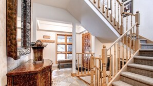 A grand staircase with wooden railings and a marble floor leading to a room with a large window. - Luxury Lodge with Breathtaking Views (Mountain Village)