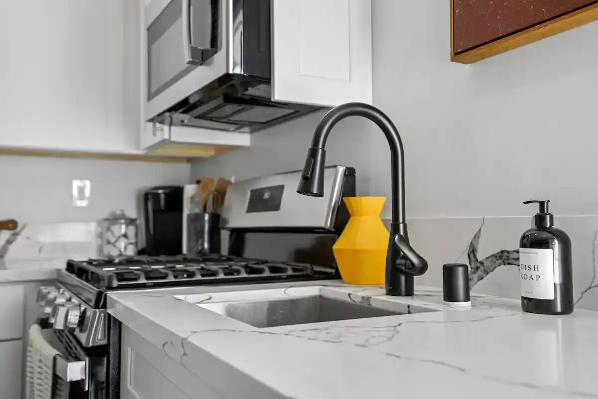 A modern kitchen with a stainless steel sink, a yellow soap dispenser, and a dish soap bottle.