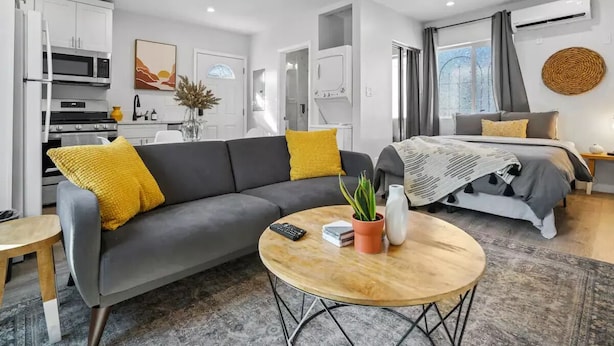 A modern, well-lit living area with a sofa, coffee table, and a bed with a patterned blanket. - Adorable studio close to DTLA (Alhambra)