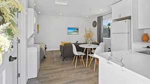 A modern kitchen with white cabinets, a marble countertop, and a dining area with a round table and chairs. - Adorable studio close to DTLA (Alhambra)