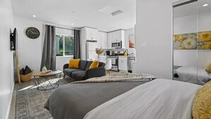 A modern hotel room with a large bed, a sofa, a dining area, and a kitchen. - Adorable studio close to DTLA (Alhambra)