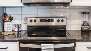 A kitchen with a stainless steel stove, a microwave above it, and a blender on the counter. - Beautiful chic modern one bedroom (Colorado Springs)