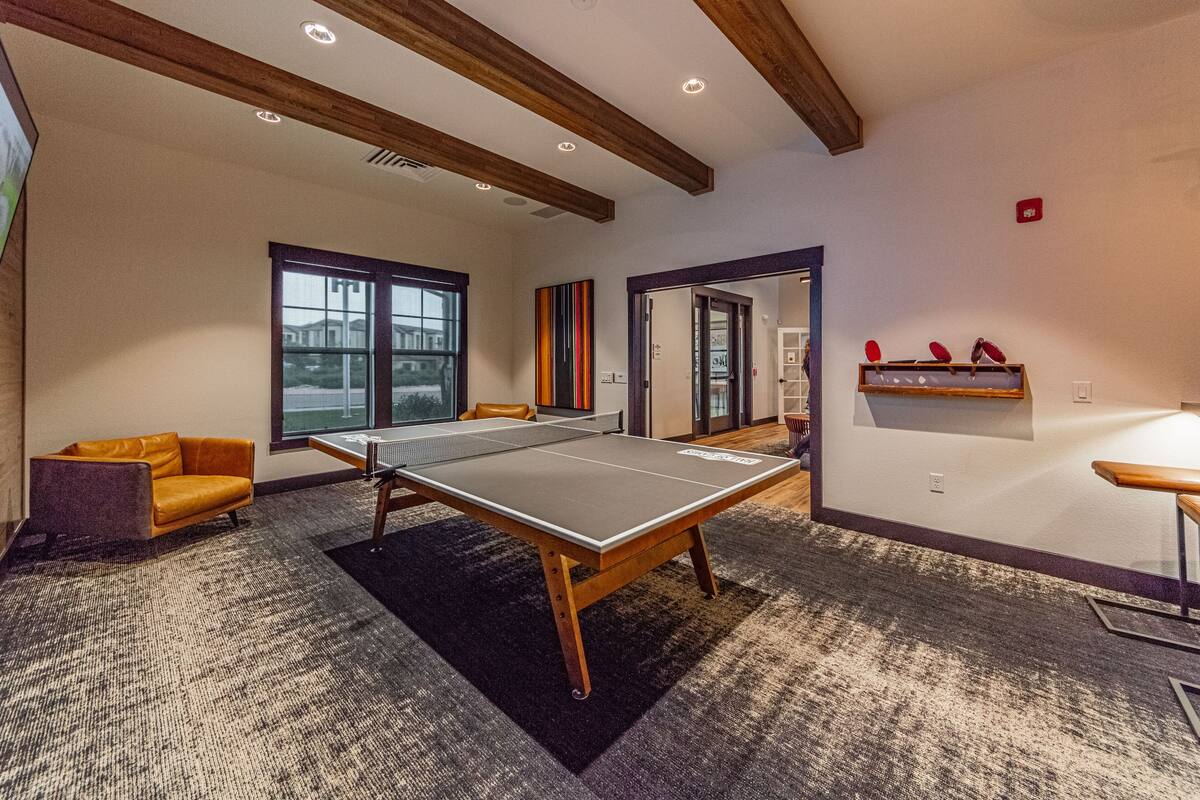 A room with a ping pong table, a sofa, and a window with a view.