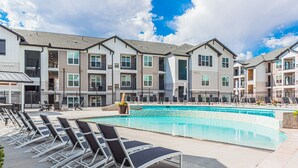 A pool area with lounge chairs and a building with multiple balconies. - Beautiful chic modern one bedroom (Colorado Springs)