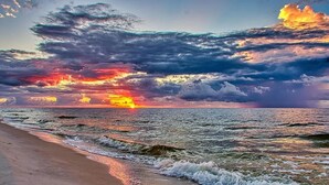 A beach with waves and a sunset.