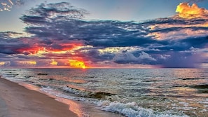 Uma praia com ondas e um pôr do sol.