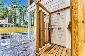 Uma porta de madeira com uma pequena janela, uma piscina e um deck de madeira.
