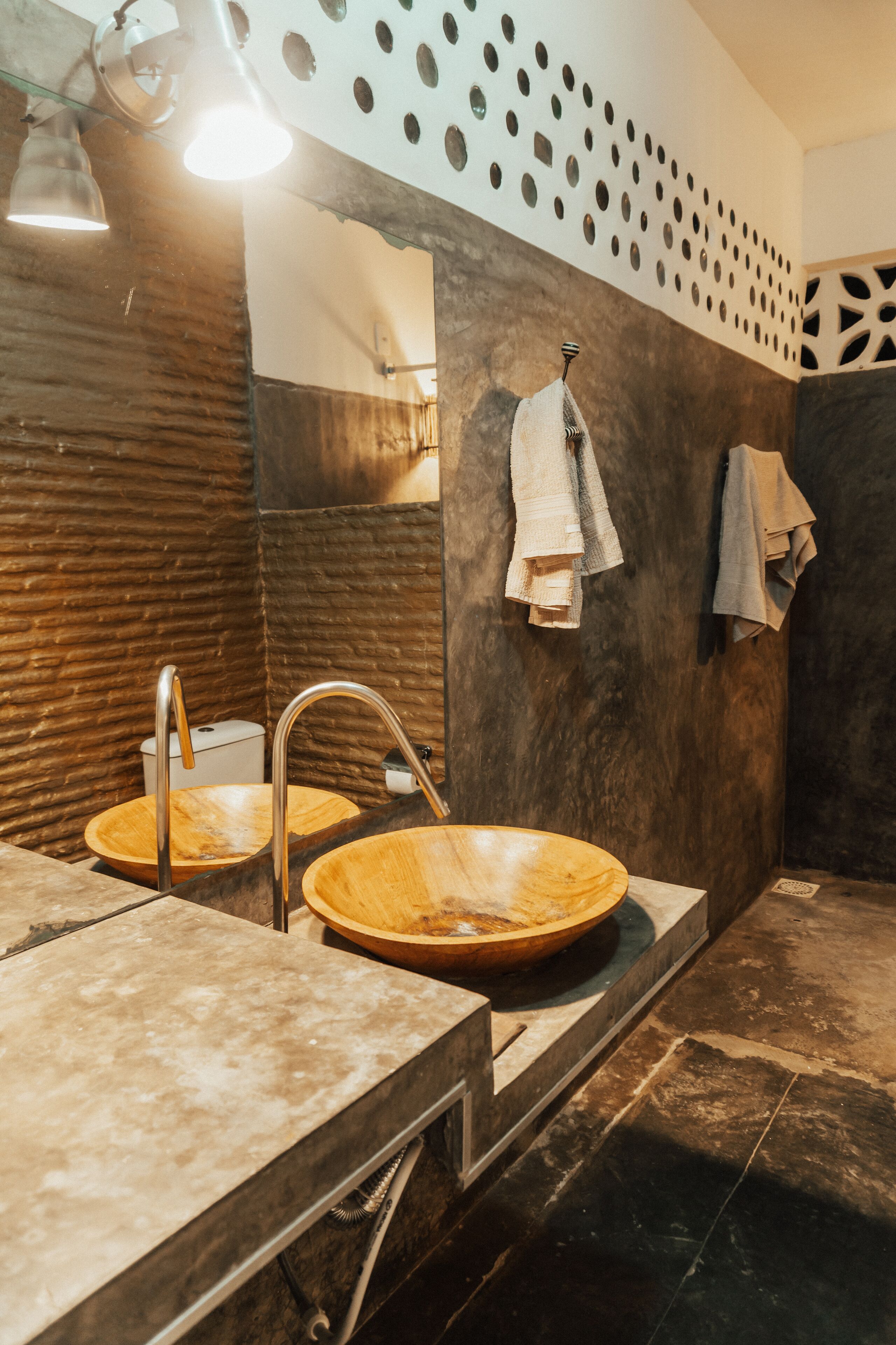 Un baño con dos lavamanos de madera, un espejo y toallas colgadas en un perchero.
