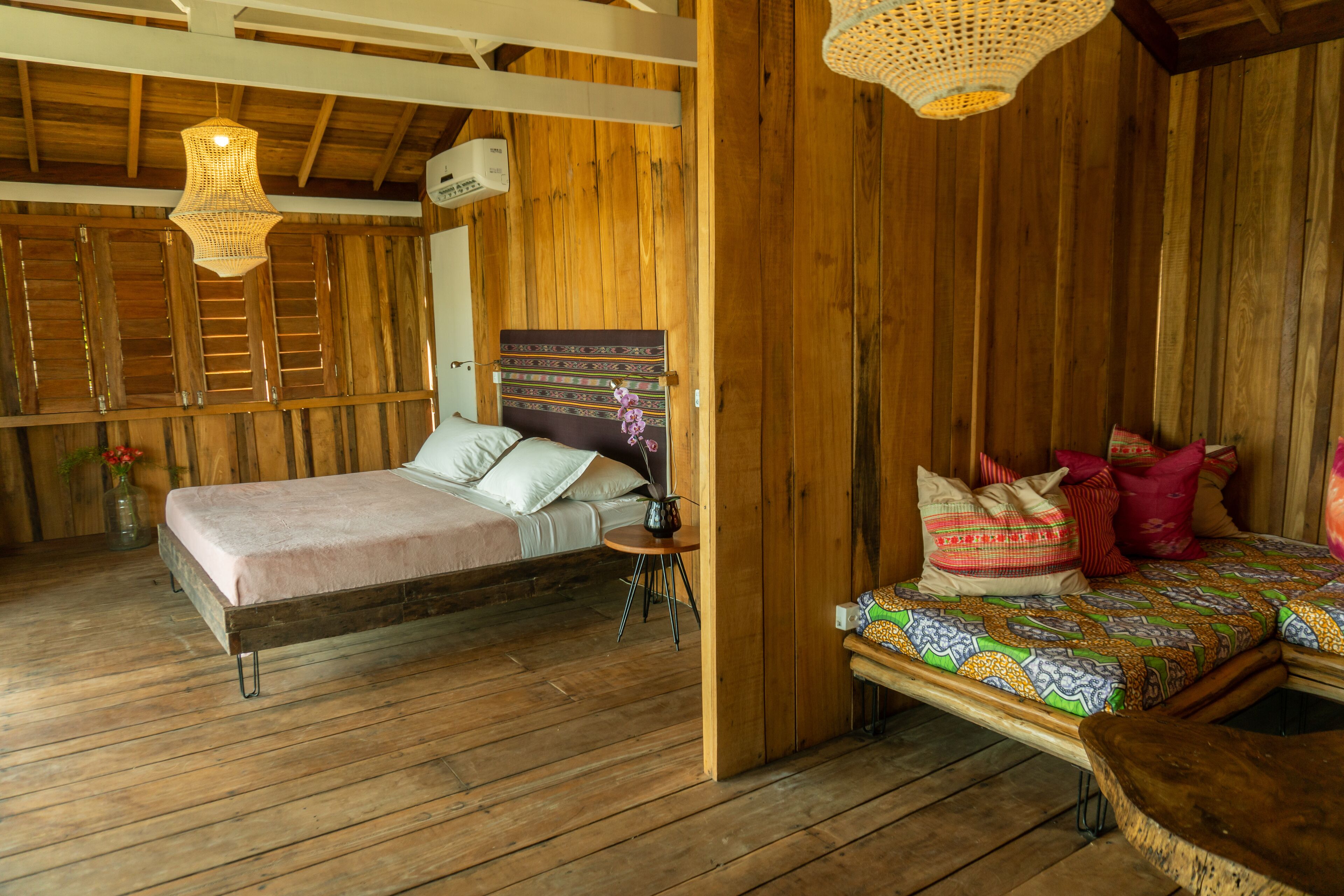 A wooden room with a bed, a small table, and a bench.