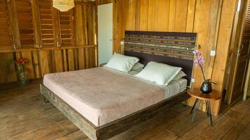 A wooden room with a bed, a small table, and a hanging light fixture.