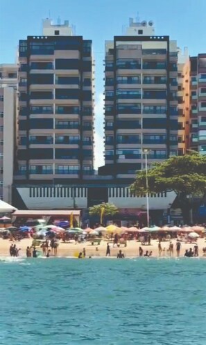 A beachfront with high-rise buildings in the background and a crowded beach area.