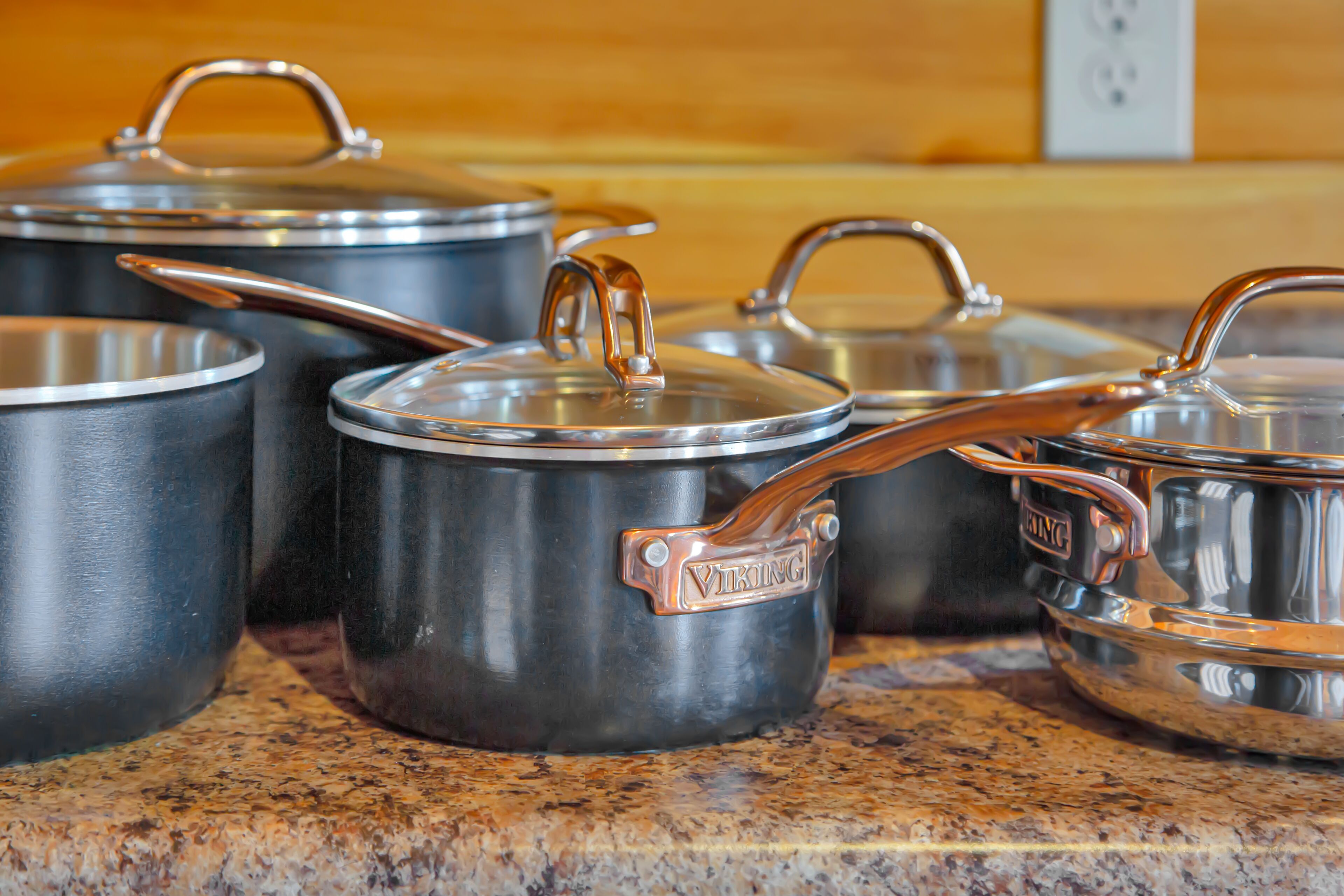 A set of stainless steel pots with lids on a granite countertop.