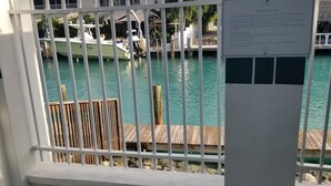 Un espace piscine avec vue sur un port de plaisance, une terrasse en bois et un panneau indicateur.