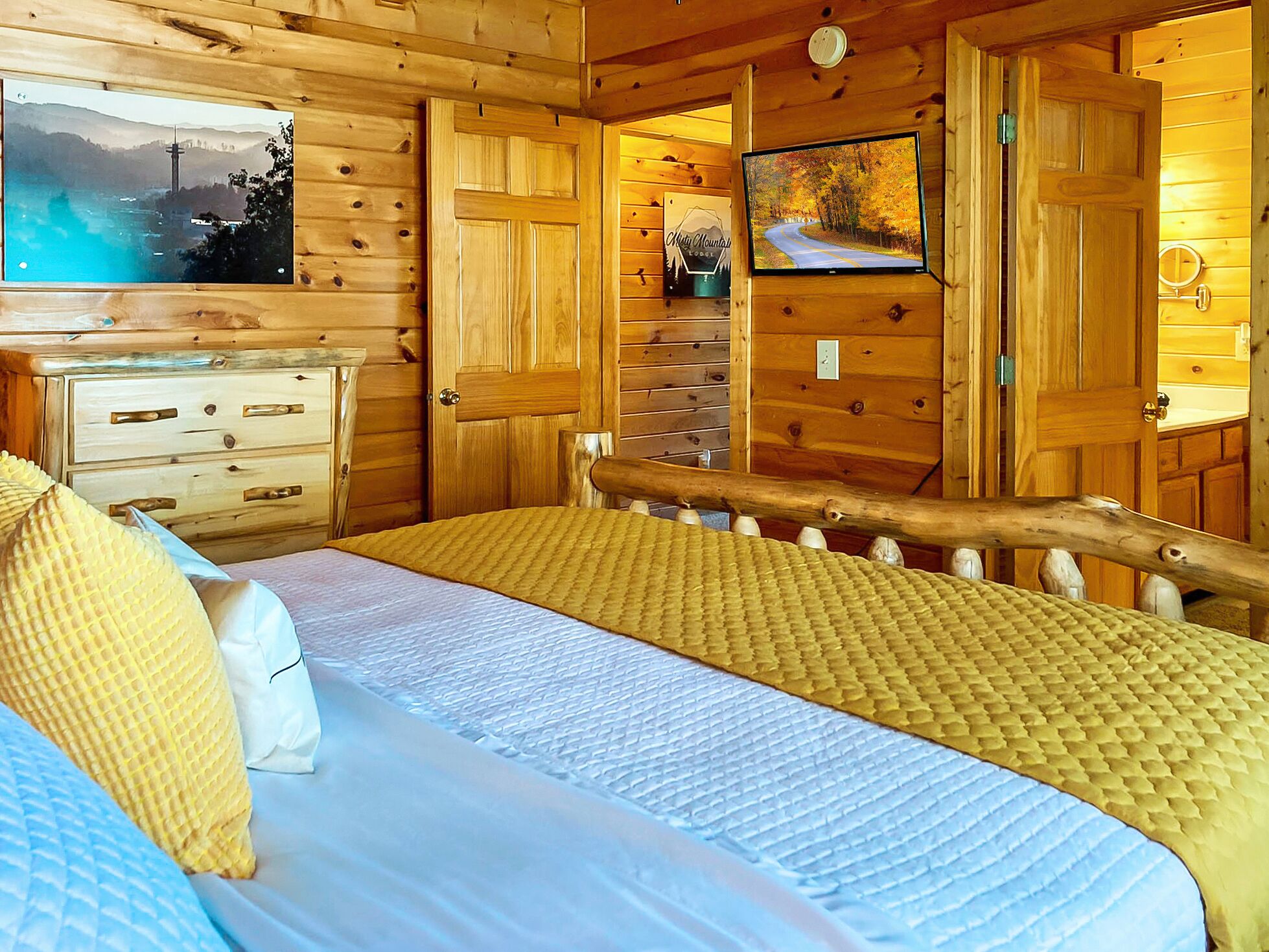 Ein Zimmer in einer Holzhütte mit einem Bett, einem Schminktisch, einem Fernseher und Blick auf eine Berglandschaft.