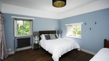 A bedroom with a bed, two bedside tables, a window, and a radiator.
