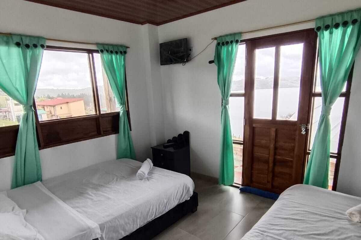 Una habitación con dos camas, un televisor en la pared y una ventana con cortinas.