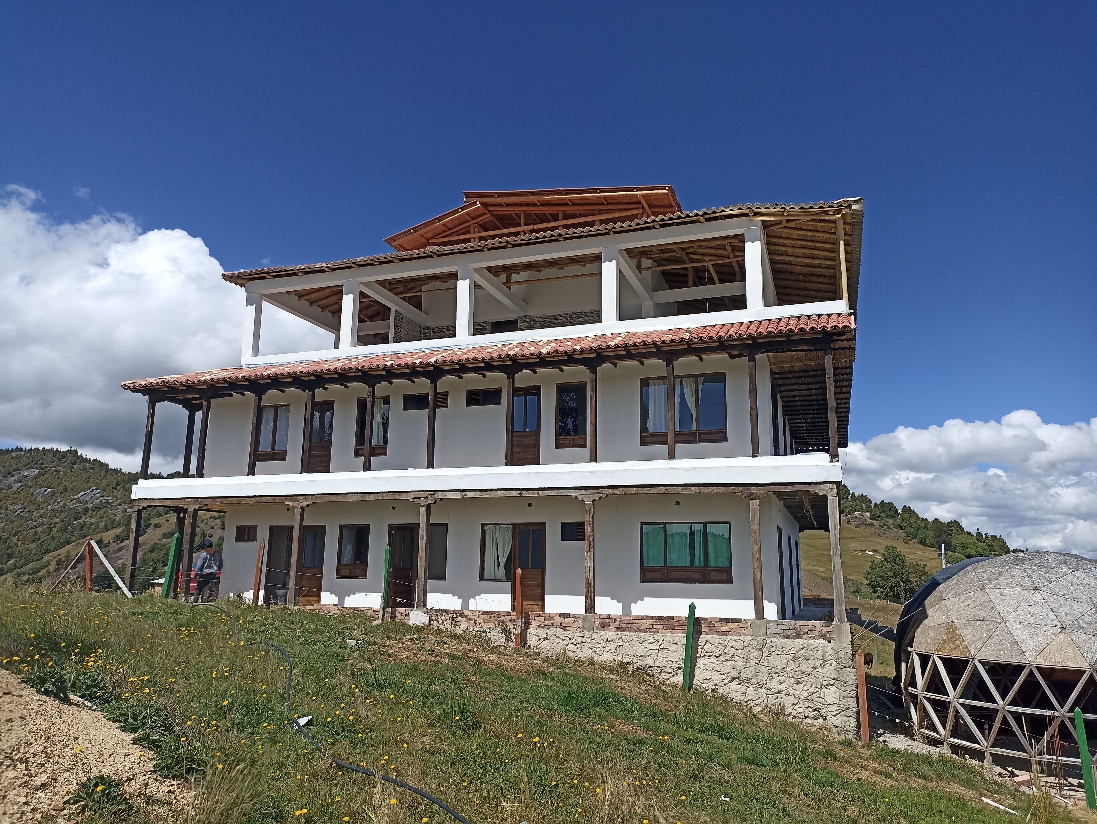 A two-story building with a tiled roof, multiple windows, and a balcony.