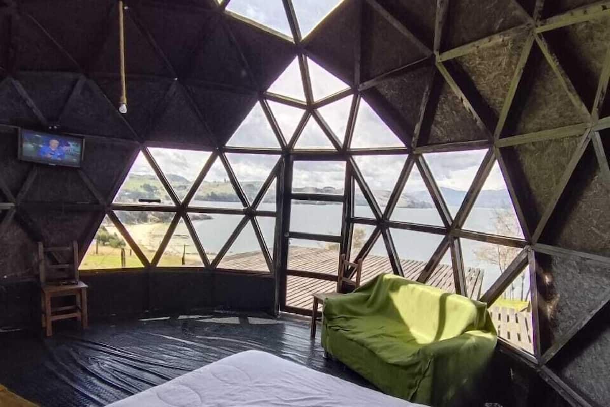Una habitación con cama, televisión y vista a un lago.