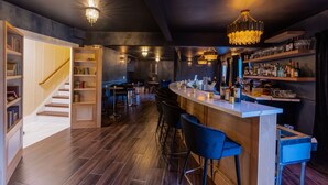 Un espace bar moderne avec un escalier en bois, des tabourets de bar et un lustre.