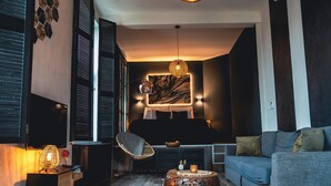 Una sala de estar moderna con un sofá, una mesita redonda, un sillón y una lámpara de pared.