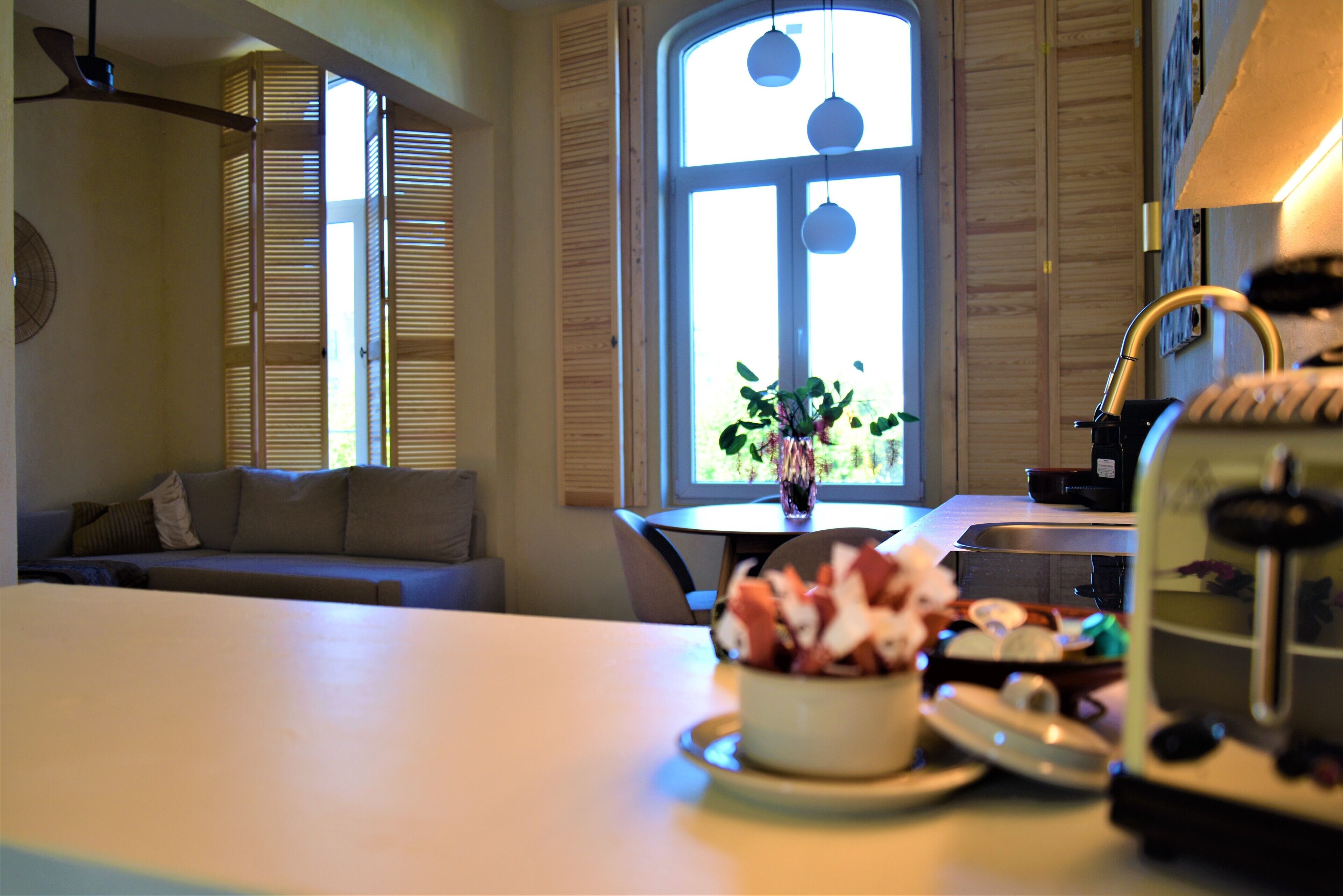 A kitchen with a dining table, a bowl of fruit, and a toaster.