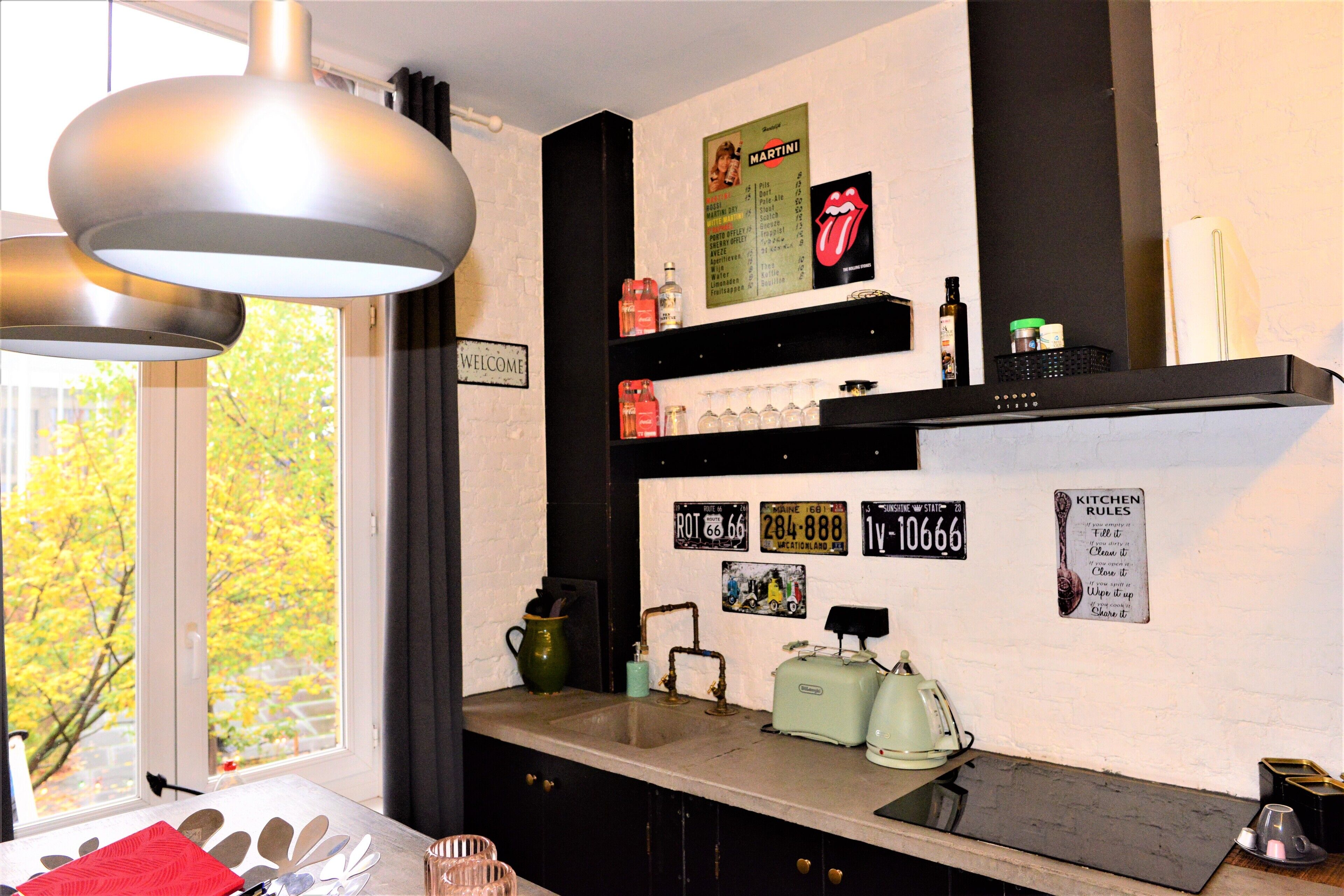 A kitchen with a window, a sink, a green kettle, and a vintage radio.