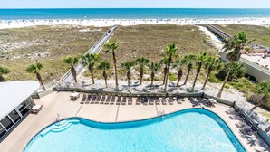 A swimming pool with a deck area, surrounded by palm trees and a beach in the background. - Tidewater 307 | Perfect Location, Magnificent Views | Indoor/Outdoor Pools (Orange Beach)