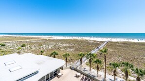 A beach view from a building with a patio area, palm trees, and a sandy beach. - Tidewater 307 | Perfect Location, Magnificent Views | Indoor/Outdoor Pools (Orange Beach)