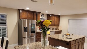 Eine moderne Küche mit Granit-Arbeitsplatten, Edelstahlgeräten, Holzausstattung und einer dekorativen Vase mit Blumen.