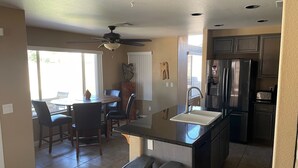 A modern kitchen with a central island, stainless steel appliances, and a dining area with a table and chairs. - Spacious family home with private pool in a safe, quiet neighborhood. (Glendale)