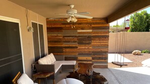 A modern outdoor seating area with a wooden wall, a ceiling fan, and a rustic rug. - Spacious family home with private pool in a safe, quiet neighborhood. (Glendale)