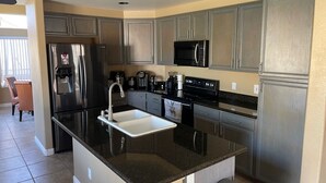A modern kitchen with stainless steel appliances, a black granite countertop, and light-colored cabinetry. - Spacious family home with private pool in a safe, quiet neighborhood. (Glendale)