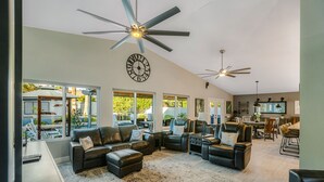 A spacious living room with leather sofas, a large rug, ceiling fans, and a clock on the wall. - Scottsdale Gem - Remodeled, Pool, Hot Tub (Scottsdale)