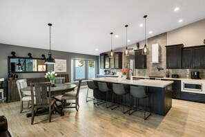 A modern kitchen with a central island, bar stools, and pendant lighting.