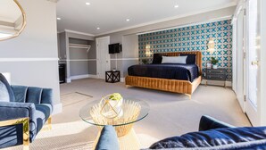 A modern bedroom with a bed, a glass coffee table, and a blue sofa.