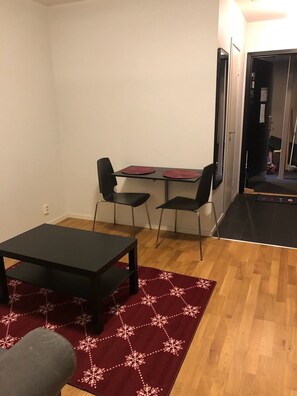 Cozy living space with a minimalist design, featuring a small table, two chairs, and a red rug.
