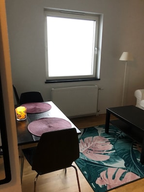Cozy room with a dining table, chair, and decorative candle, featuring a window and radiator.