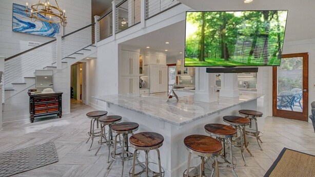 Una cocina amplia con una isla grande, taburetes de bar y un televisor montado en la pared.